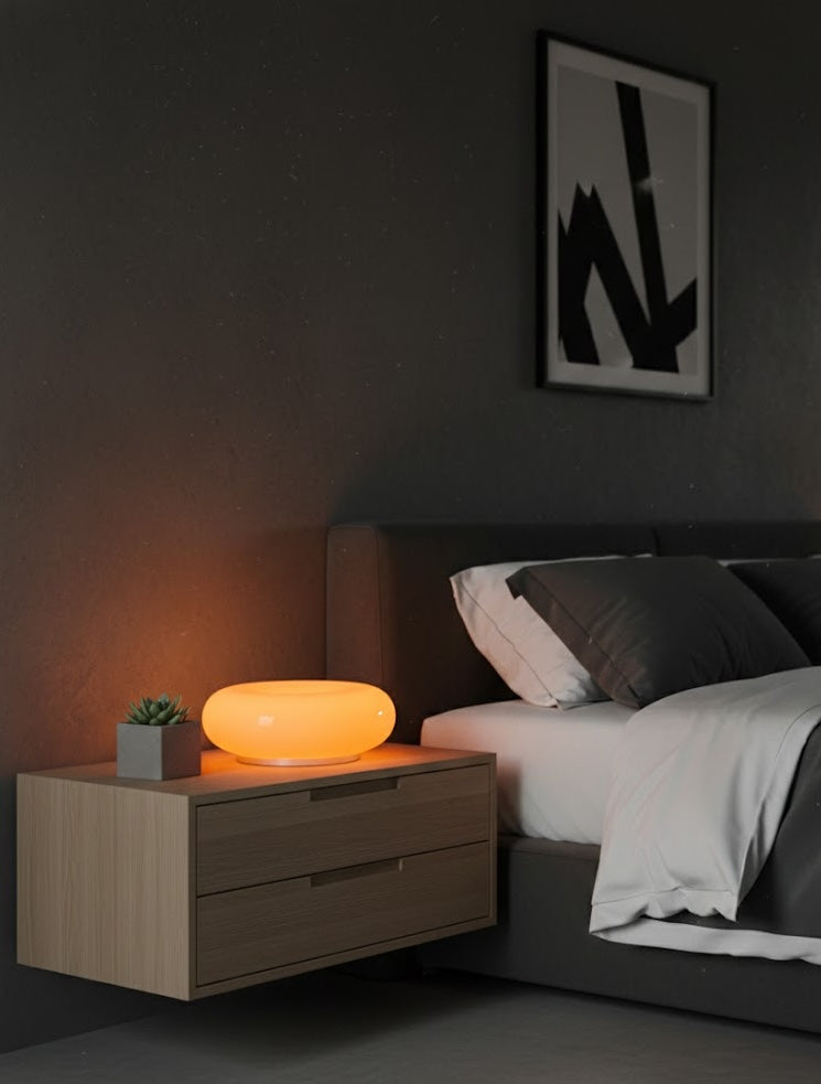 Bedroom with a nightstand featuring a glowing lamp and abstract art on the wall