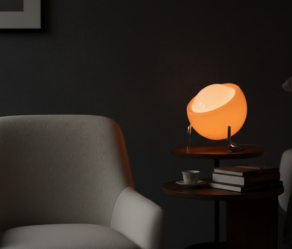 Orange table lamp on a side table in a dimly lit room with a chair and books